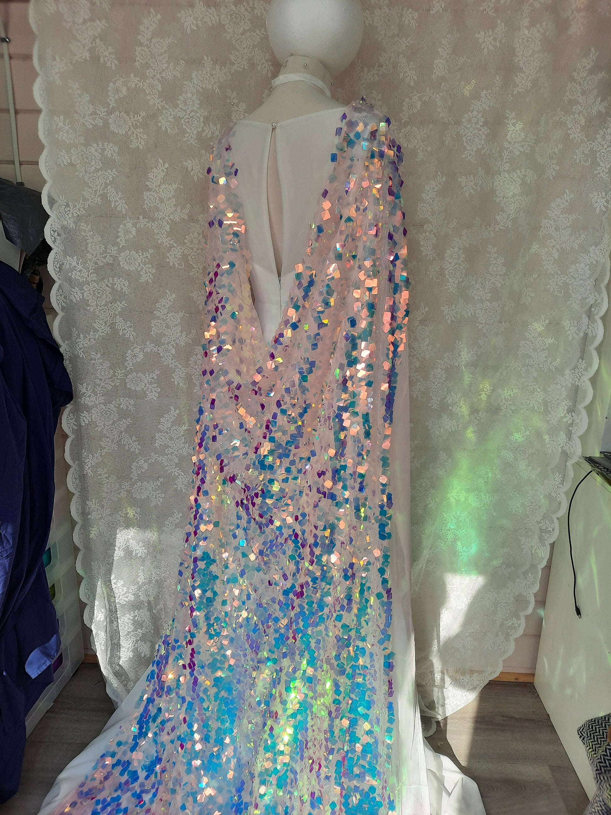 May include: A pink sheer fabric with iridescent sequins in shades of blue, pink, and purple. The sequins create a shimmering effect.